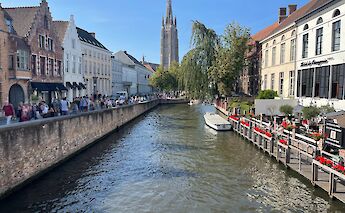 A canal in Bruges lined with historic buildings and a boat on the water.