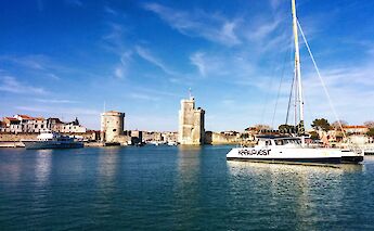 Coastal view with boats and historic towers in La Rochelle, France.