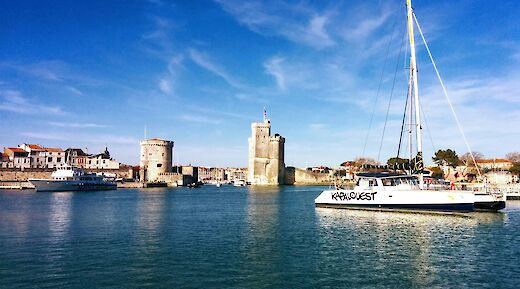 Coastal view with boats and historic towers in La Rochelle, France.