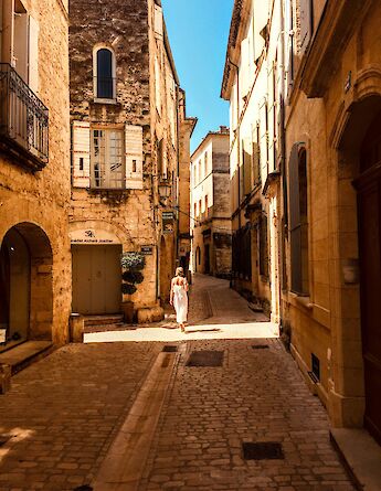 Woman walking through the streets of Uzes, France. Unsplash:Luc Vlekken
