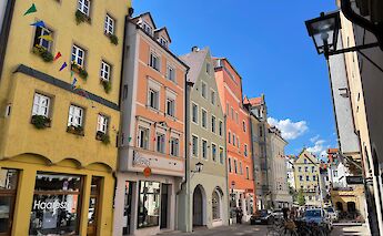 A street in Regensburg, Germany, lined with colorful historic buildings under a clear blue sky.