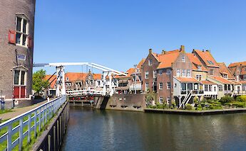 A canal lined with historic buildings and a drawbridge in Enkhuizen, North Holland.