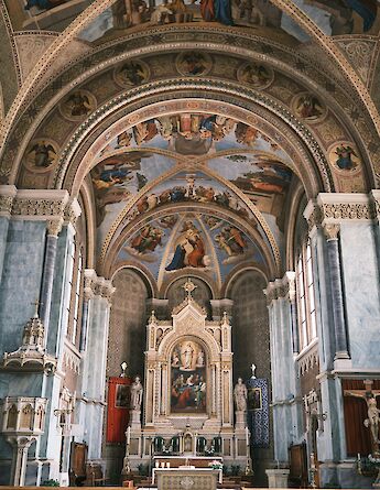 The interior of a church with ornate frescoes and decorations in Bruneck, South Tyrol, Italy.