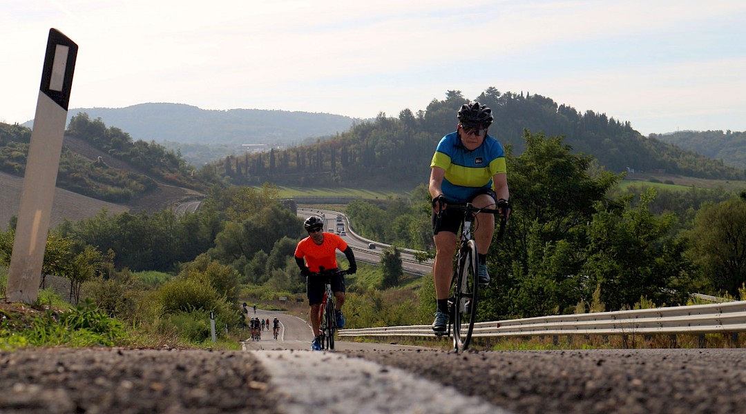 A cyclist on a quiet road through the Tuscan hills