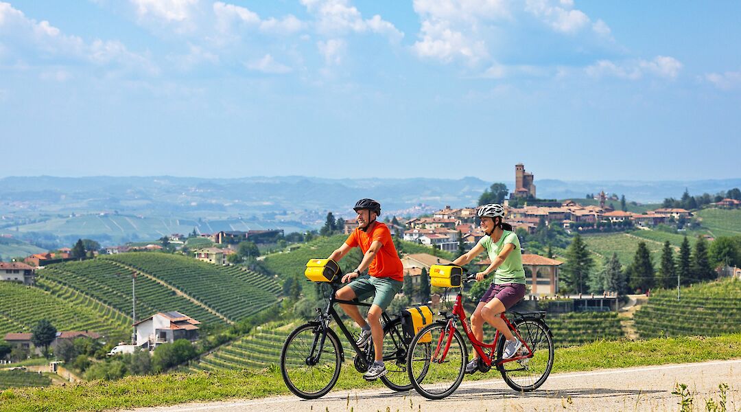 Two cyclists riding past vineyards in Piedmont