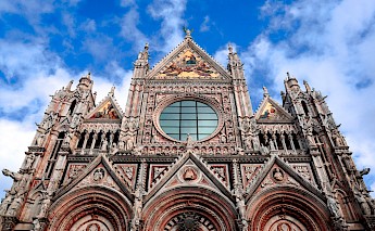 Facade of Siena Cathedral, displaying intricate Gothic architecture and detailed sculptures.