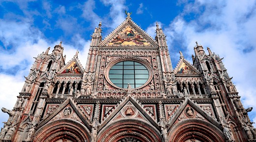 Facade of Siena Cathedral, displaying intricate Gothic architecture and detailed sculptures.