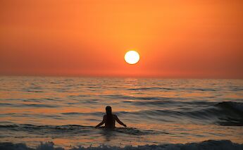 Swimming in the sea at sunset in Cadiz, Spain. Unsplash:Txema Hernandez