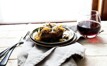 Meat served with onion and wine. Unsplash:Katherine Chase