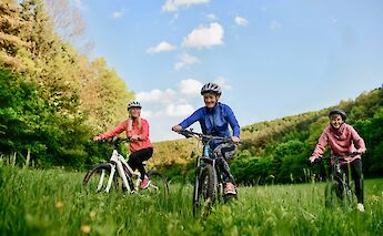 Three women biking through grass. Getty Images@Unsplash
