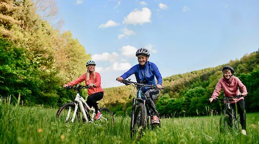 Three women biking through grass. Getty Images@Unsplash