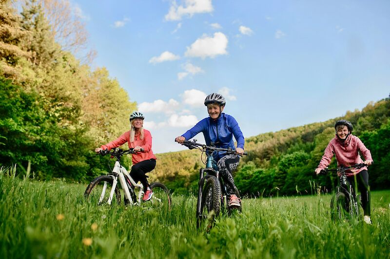 Three women biking through grass. Getty Images@Unsplash