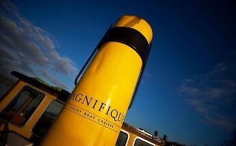 A close-up of a yellow smokestack with the text "MAGNIFIQUE" painted on it, set against a&hellip;