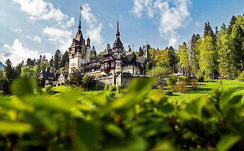 View of Peles Castle through foliage, Romania. Majkl Velner@Unsplash