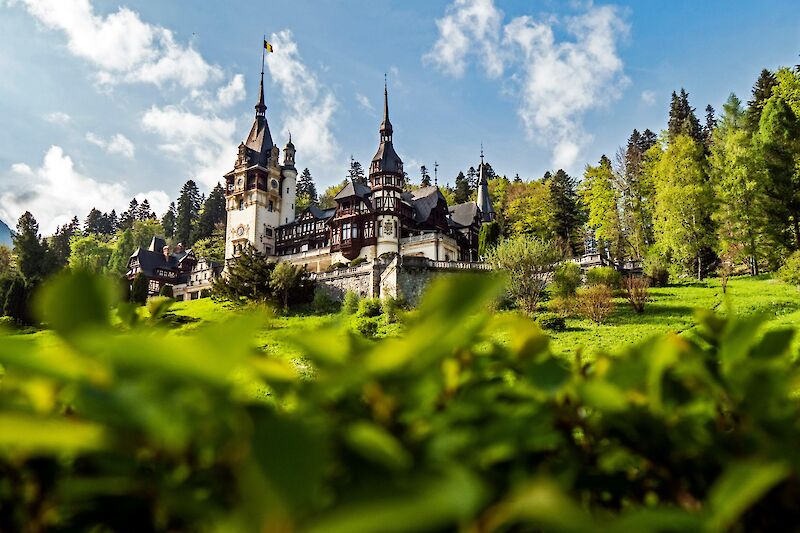 View of Peles Castle through foliage, Romania. Majkl Velner@Unsplash
