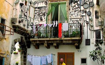 A cyclist standing beside a bicycle in a courtyard, with a building facade adorned with various…