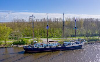 A large sailing vessel named Leafde fan Frysl&acirc;n is docked alongside a tree-lined canal under a&hellip;