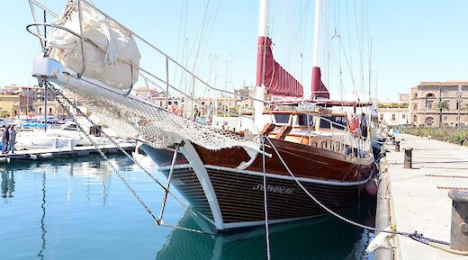 The bow and side view of the wooden sailing boat named Sundial docked in a marina.