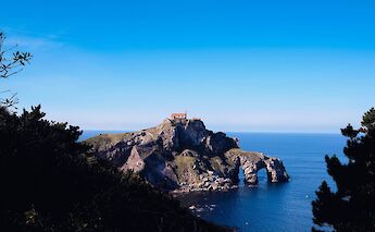 San Juan de Gaztelugatxe viewed through trees, Spain. Unsplash:Jose Rago