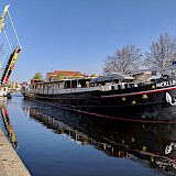 Merlijn boat is seen in a canal near Haarlem with a raised drawbridge in the background on a clear day.