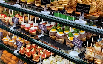 An assortment of Spanish tapas displayed in a glass case.