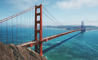 A view of the Golden Gate Bridge in San Francisco, stretching over the water with the city skyline visible in the distance.