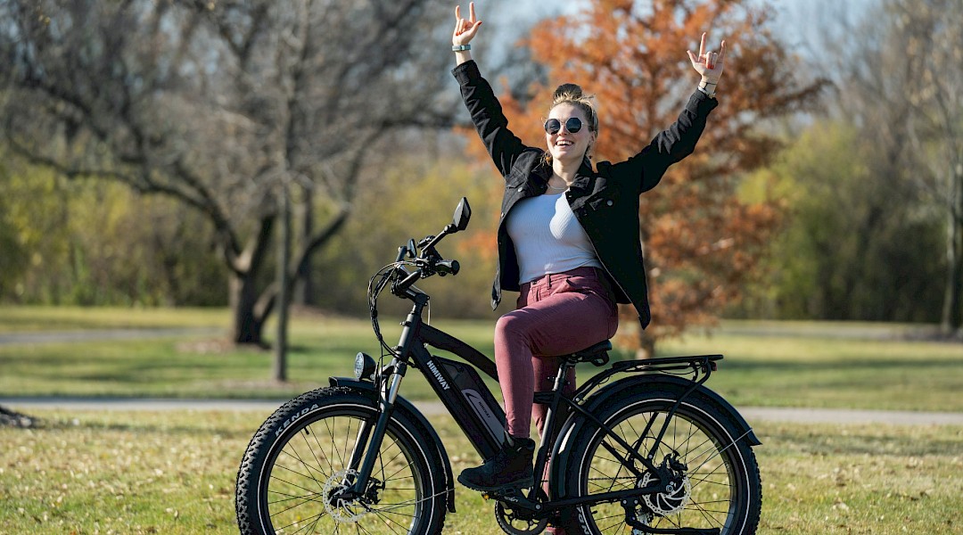 Woman on electric bike with hands in the air. Unsplash:Himiway Bikes
