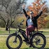 Woman on electric bike with hands in the air. Unsplash:Himiway Bikes