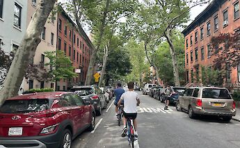 Cyclists ride through a residential street in Brooklyn. Unsplash: Bernd Dittrich