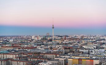 An aerial view of Berlin at dusk, showcasing the TV Tower and cityscape under a gradient sky.