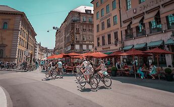 Cycling past restaurants, Munich, Germany. CC:Radius Tours