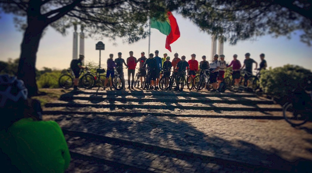 Standing with bikes beneath the flag. Lisbon Cycle Tours