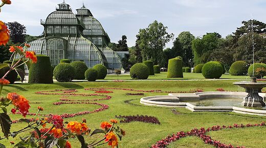 Green trees and red flowers at Palmenhaus, Schonbrunn, Vienna. Unsplash:Angie Ca Ro