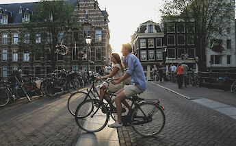 People cycling through Amsterdam at dusk, Amsterdam bike tour, Holland. Sabina Fratila@Unsplash
