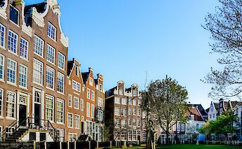 Historic gabled houses in Amsterdam, Holland, surrounding a small grassy courtyard with a statue.