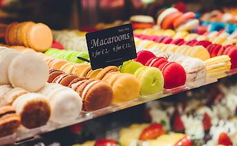 An array of colorful macaroons on display in a bakery.