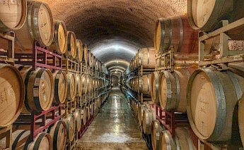 Barrels are stacked along the sides of a tunnel in a California wine cellar.