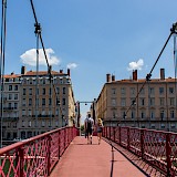 French couple holding hands while crossing Lyon's Saint-Vincent bridge. Laurine Peyrard@Unsplash
