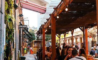 People dining at an outdoor space in Lisbon, surrounded by greenery and urban architecture.