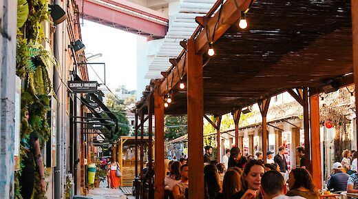 People dining at an outdoor space in Lisbon, surrounded by greenery and urban architecture.
