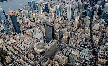 An aerial view of a densely packed urban landscape with numerous skyscrapers and city buildings in New York City.