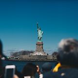 View of the Statue of Liberty behind tourists, New York, New York. Jenny Marvin@Unsplash