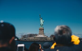 View of the Statue of Liberty behind tourists, New York, New York. Jenny Marvin@Unsplash