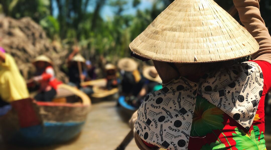 Vietnamese traditional hat worn by local boat operator through the Mekong delta river tour, Ho Cho Minh City, Vietnam. Anne Lin@Unsplash