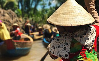 Vietnamese traditional hat worn by local boat operator through the Mekong delta river tour, Ho Cho Minh City, Vietnam. Anne Lin@Unsplash
