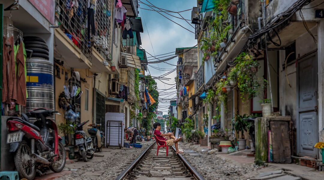 Man in a red chair on Train Street, Hanoi, Vietnam. Chor Tsang@Unsplash
