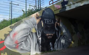 The Hague Street Art Cap on the guy in a hoodie, Mural by Patrick Goos, The Hague, Holland. Vysotsky@Wikimedia Commons