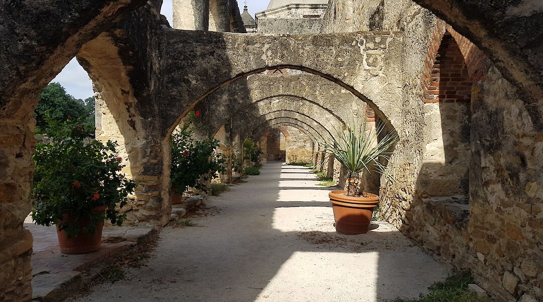 Potted plants and age-old arches in the courtyard in Mission San jose, San Antonio, Texas, USA. CC:Irid Escent