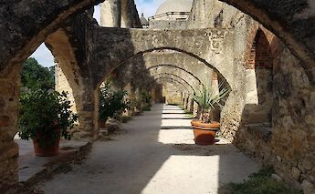 Potted plants and age-old arches in the courtyard in Mission San jose, San Antonio, Texas, USA. CC:Irid Escent