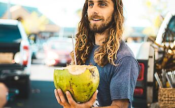 Hawaiian local presents a coconut to a customer. Chloe Leis@Unsplash